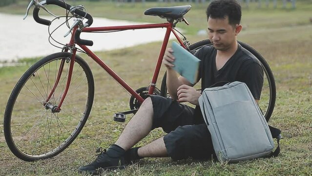 man sitting alone on the peak of the hill with bicyle and taking picture of the view