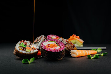 Aesthetic composition with sushi rolls on a dark background. Ready advertising banner. Healthy eating concept, seafood, salmon, shrimp, ready food.