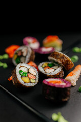 Aesthetic composition with sushi rolls on a dark background. Ready advertising banner. Healthy eating concept, seafood, salmon, shrimp, ready food.