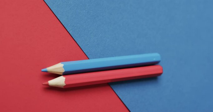 Close up of blue and red crayons on red and blue background, in slow motion