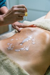Fototapeta premium Woman applying liquid with active concentrates on the patient's belly for lymphatic drainage massage