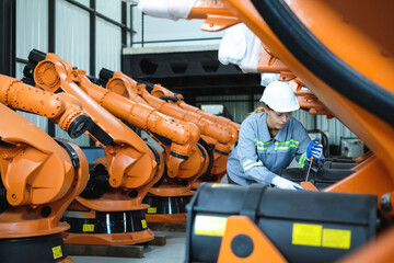 Female robot engineer wearing 
helmet and safety glasses using screwdriver to tighten the screws of...