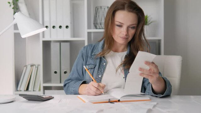 The world of finance at home, where a woman at home uses a notebook, which plays an important role in managing the household budget. Financial Literacy Keeping Records of Expenses and Income