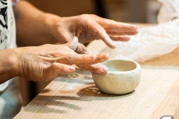 Woman's hands making a ceramic vessel from clay.