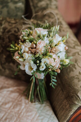 Wedding bouquet. White cut roses, green seed heads and leaves. Green stems and white ribbon and gold wedding rings.