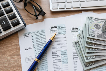 PC keyboard US dollar pen 1040 tax form on office table desktop