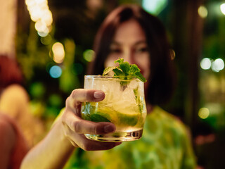 Woman hand holding a glass of Mojito With Lime and Mint. Summer mint lime refreshing cocktail...