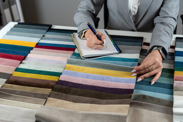 woman choose different color in fabrics catalog for upholstered furniture  at office.
