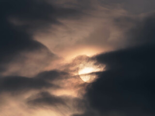 Fototapeta na wymiar Sonne teilweise von dunklen Wolken verdeckt 