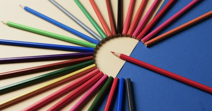 Close up of crayons arranged on beige and blue background, in slow motion