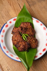 Tempe Bacem is tempeh cooked with coconut water, brown sugar, bay leaves, galangal, shallots, garlic, and coriander. Indonesian food. Served on a vintage plate.