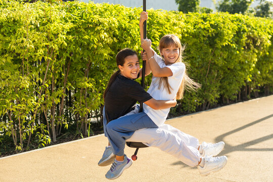 girls teenager swinging on a swing with bare feet on the green lawn of the backyard of his house