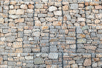 Empty grey stonewall behind wire metal mesh for protection background texture. Copy space