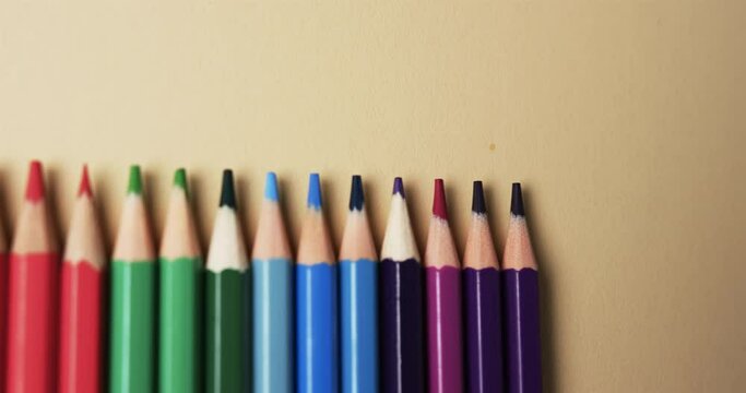 Close up of crayons arranged with copy space on beige background, in slow motion