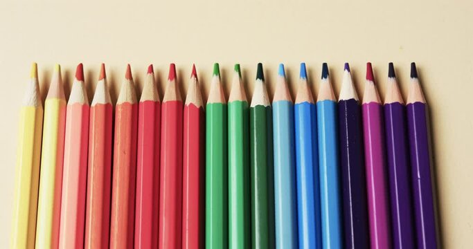 Close up of crayons arranged on beige background, in slow motion