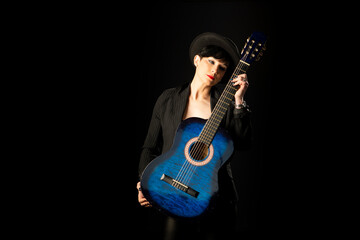 A young, beautiful woman in black with an acoustic blue guitar