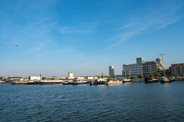 Antwerp, 20th of April, 2022, This image presents a lively scene at the Port of Antwerp. The waters in the foreground are dotted with boats and ships, implying a busy maritime hub. Across the water