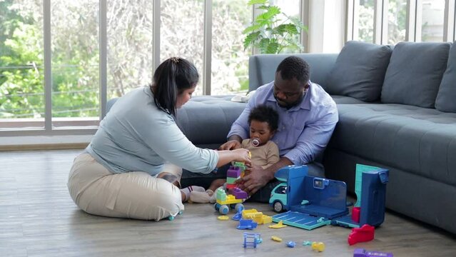 Parents and little son sit in the living room, they are playing with toys together. mixed race family concept
