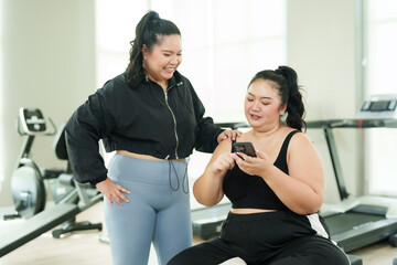 Overweight Asian woman sitting in gym, always exercise reduce belly, woman sits looks at food on...