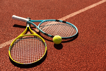 Balls and racket are lying on clay brown professional tennis court Close up of tennis balls and...