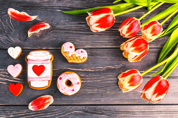 Festive gift gingerbread for Valentine's Day in the shape of a cup of coffee, hearts and a donut and a bouquet of red tulips. Happy Valentine's day greeting card