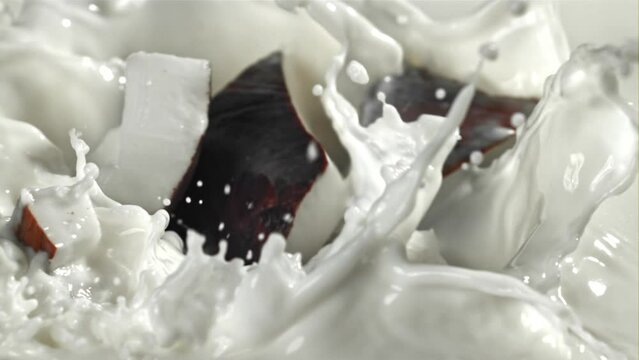 Pieces of coconut fall into the milk with splashes. Filmed on a high-speed camera at 1000 fps. High quality FullHD footage