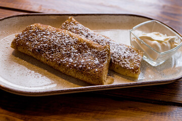 Pancakes with sour cream sprinkled with sugar on a plate on a wooden table