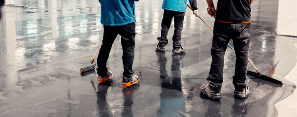 Workers applies gray epoxy resin to the new floor.