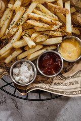 French fries with ketchup and mayonnaise in a basket on a gray background