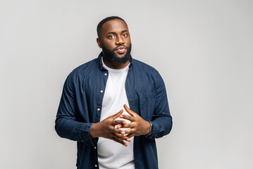 A contemplative African-American man stands with clasped hands, exuding a sense of thoughtful...