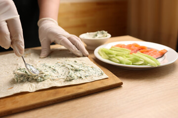 A layer of prepared cheese is applied to pita bread. Preparation of roll with fish and vegetables
