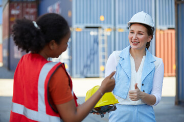 boss giving helmet to worker or engineer and thumbs up pose in containers warehouse storage