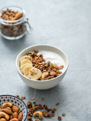 Granola or muesli with yogurt and banana on a light table.