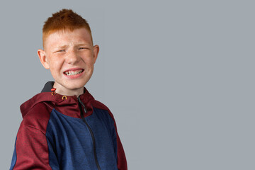 A teenager with red hair looks at the camera, grimaces and smiles evilly.