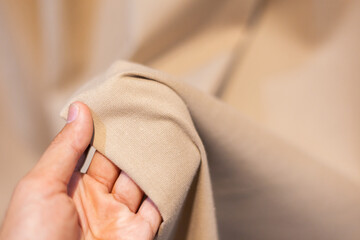 Hand Soft touch natural fabric. The hand is holding the white cloth for choosing a good fabric.