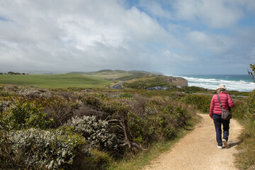 A tourist wanders on a path in Port Campbell National Park, Victoria, Australia, off the the Great Ocean Road overlooking the Bass Strait.