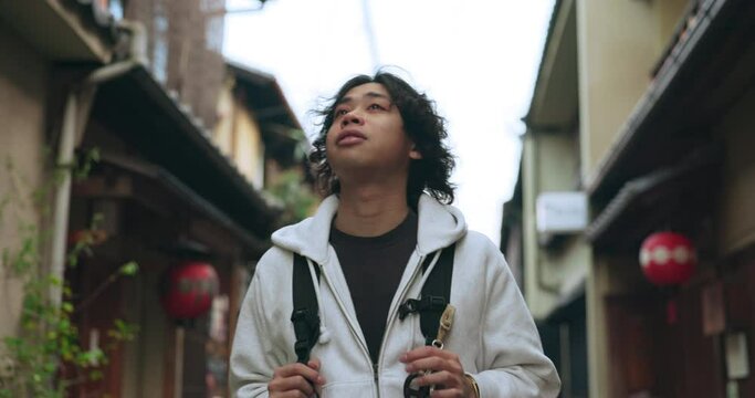 Man, Japan and travel or explore city with backpack for adventure, vacation or cultural history. Asian person, walking and kyoto or urban buildings for education as tourist for holiday or trip