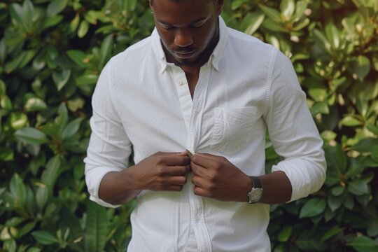 A man is seen adjusting his white shirt. This image can be used to portray professionalism, personal style, or attention to detail
