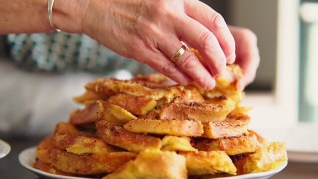 Slow Motion close up of senior woman hands serving traditional spanish dessert of torrijas for easter and lent.