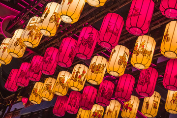 a lot of colorful lamps hanging from a ceiling at an oriental market