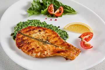 Pan-seared salmon steak with fresh spinach on white plate, perfect for healthy lifestyle and seafood cuisine presentations