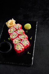 California roll with tobiko and crab, served on a black slate with soy sauce and wasabi