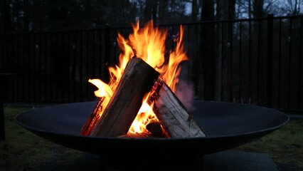 fire burning in fire pit (wood logs ablaze with orange flames) outdoor camping, relaxing scene