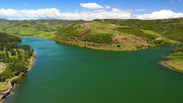 The drone runs along a lake and approaching a small encampment. About gold, oilfield, mining, gold mining, currency, stock market, Lake, sieve.