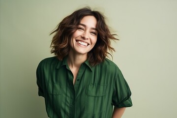 Fototapeta premium Portrait of a happy young woman smiling at camera over green background.