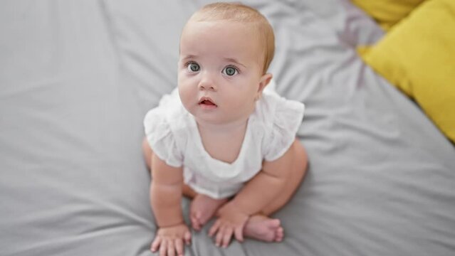 Adorable baby, a little toddler in comfy clothes, sitting relaxed on the bed sheet with a serious face in the morning! indoor lifestyle in the infant's room that exudes comfort and relaxation