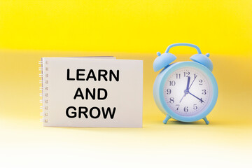 Learn and grow the symbol. Conceptual words Learn and Grow on notepad and yellow background with clock. Business, learning and growth concept.