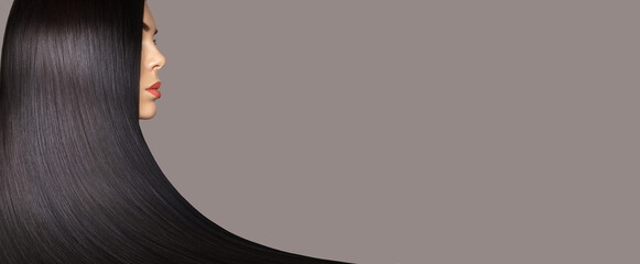 Hair care. Hair cosmetics. Beauty fashion profile portrait of young brunette woman with smooth healthy long hair posing against gray background.