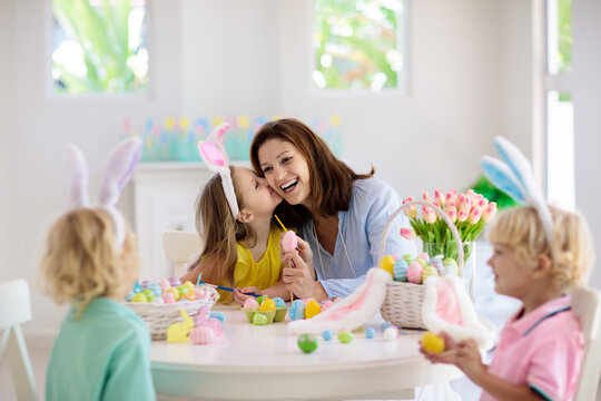 Mother and kids, family coloring Easter eggs.