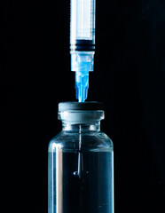 Vaccine vials and medical syringes on black